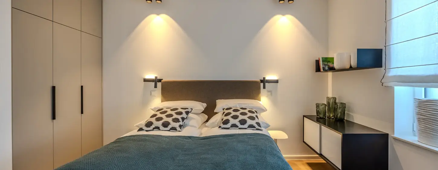 Schlafzimmer mit raumhohem Einbauschrank und schwebendem Nachttisch in einem vollständig möblierten Apartment L