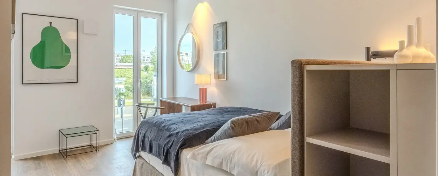 Schlafzimmer mit offenen Regalen und hellem Fenster in einem vollständig möblierten Apartment in Frankfurt Sachsenhausen