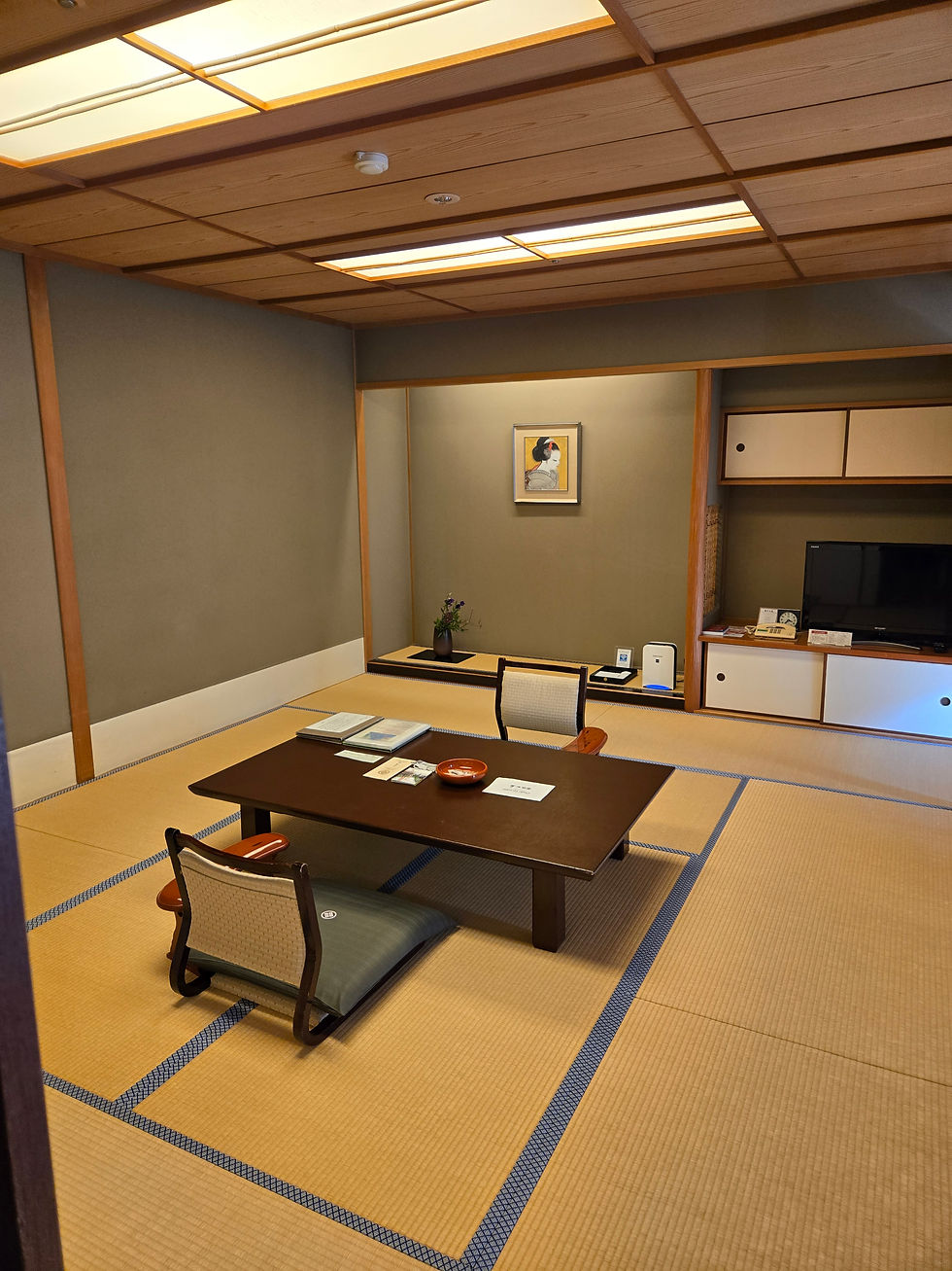 Traditional tatami mat room with low table, chairs, and shoji doors at Nishimuraya Hotel Shogetsutei in Kinosaki Onsen, Japan.