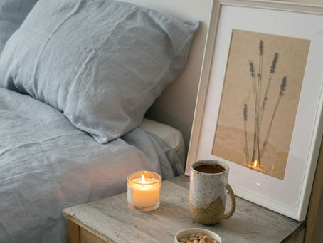 Calm bedroom with soft lighting, candle, and cozy bedding creating a relaxing nighttime atmosphere for better sleep.