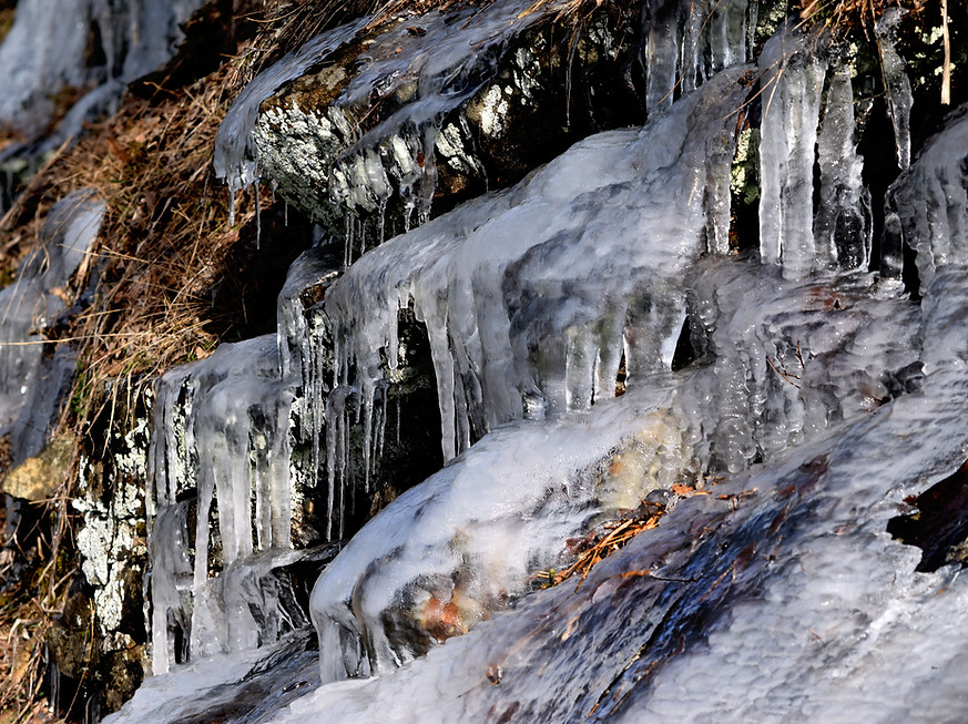 Ice covering a dark rocky surface in layered translucent textures.