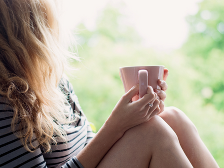 Woman sitting quietly with a cup of tea by a window – calm moment representing hormone support through perimenopause