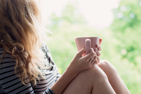 Woman sitting quietly with a cup of tea by a window – calm moment representing hormone support through perimenopause