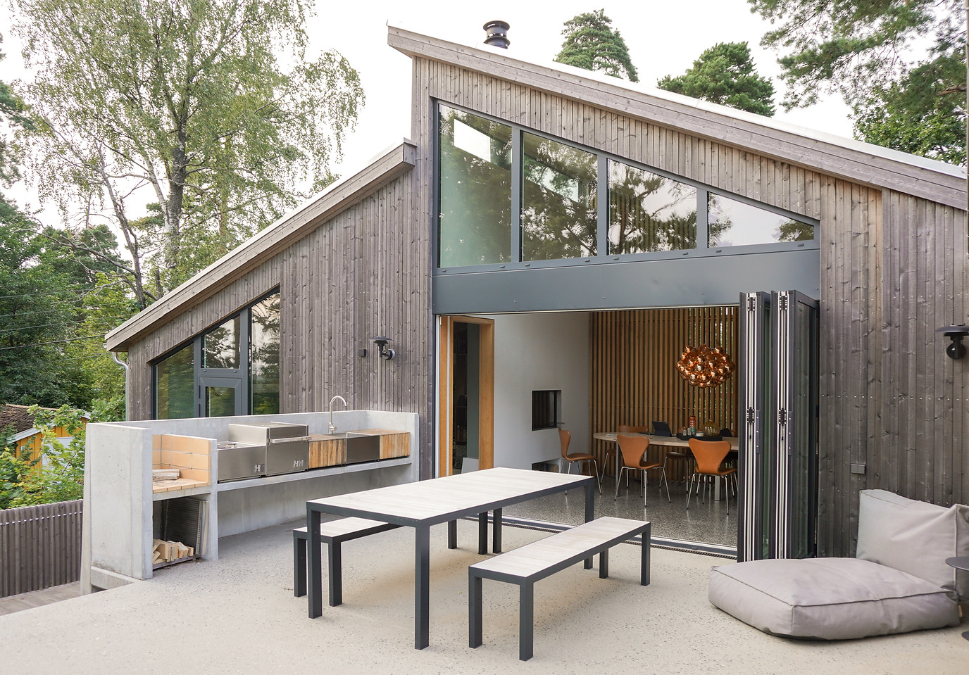 Terrasse med utekjøkken Roshult Foldedør Grånet kledning Terrassogulv Spilevegg Designermøbler Arkitekttegnet enebolig