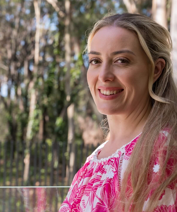 Jenny Adams outdoors beside trees in pink floral top
