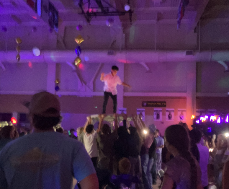 A student being held up on a table in the excited crowd.