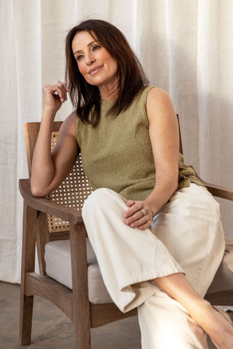Close up of female model against neutral backdrop styled for SS25 in cream and green