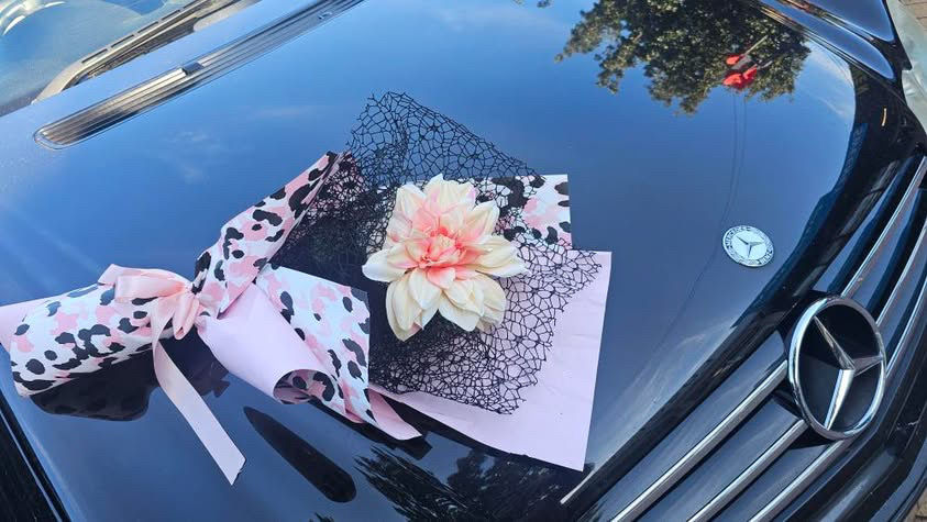 Thumbnail: Leopard pearl sheets pink wrapped in bouquet laying on a car
