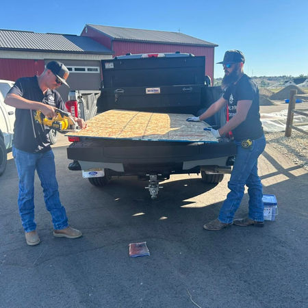 Hilltop Roofing contractors unloading shingles and building materials from a truck bed for a Make-A-Wish community project.