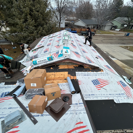 The roof deck partially covered with white synthetic underlayment featuring red and blue branding.