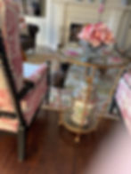Cat sits near a gold table with flowers and a decorated vase.