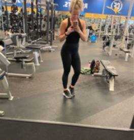 Woman takes gym selfie in fitness center, workout in progress.