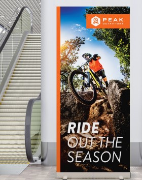 Mountain biker riding over rocks, Peak Adventures banner reads, Ride Out The Season.
