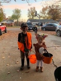 Two children in costumes holding Halloween buckets on a street Happy Halloween!