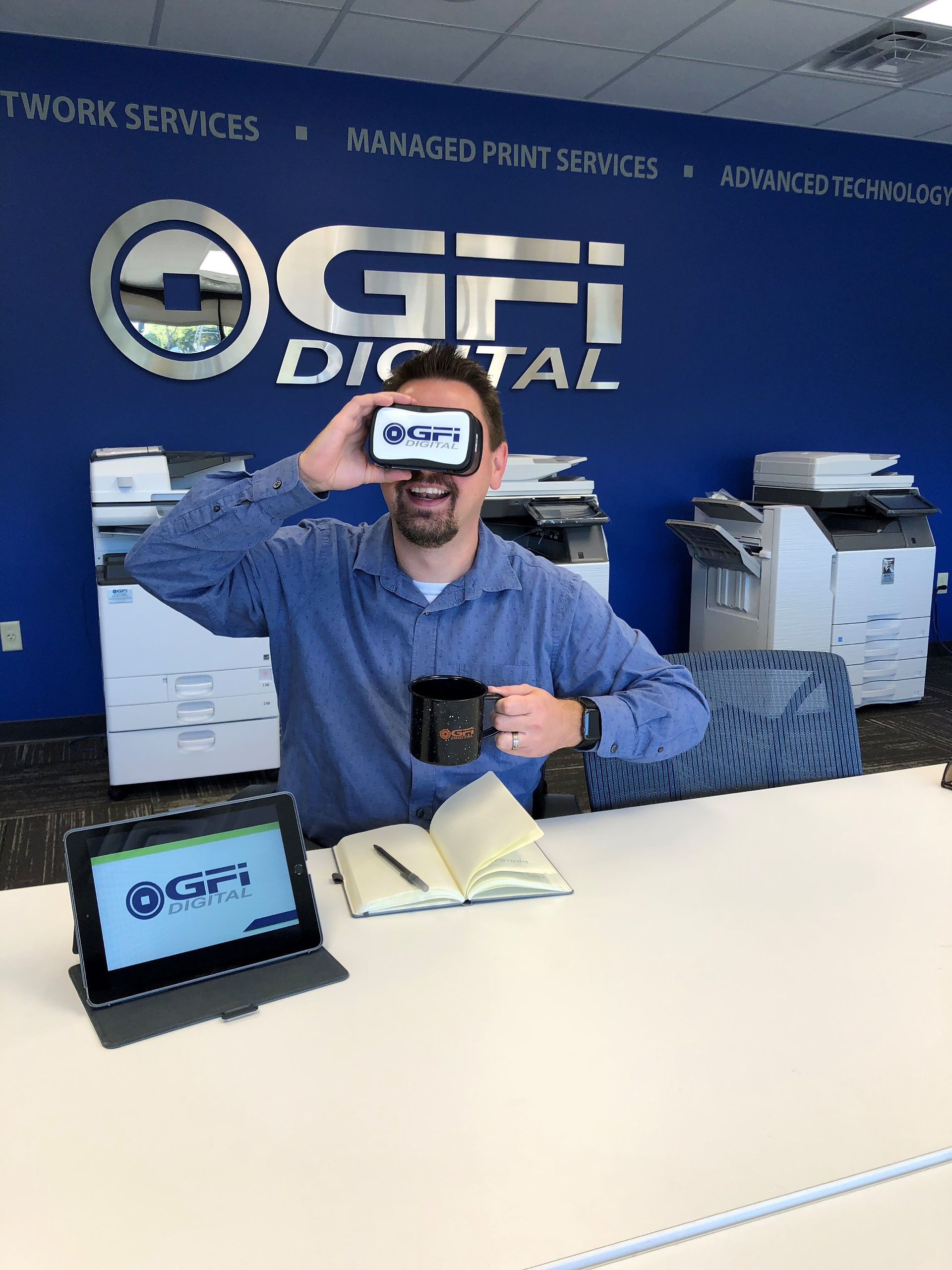 Man holds phone, showing GFI logo in office with GFI DIGITAL logo.