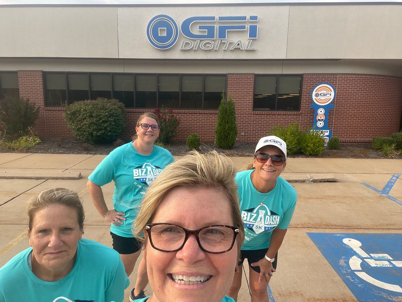 Four women posing for a photo in front of the GFI building
