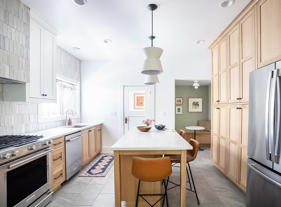 Full kitchen view of two tone white and light wood cabinets with counter to ceiling vertical tile and tiled range hood