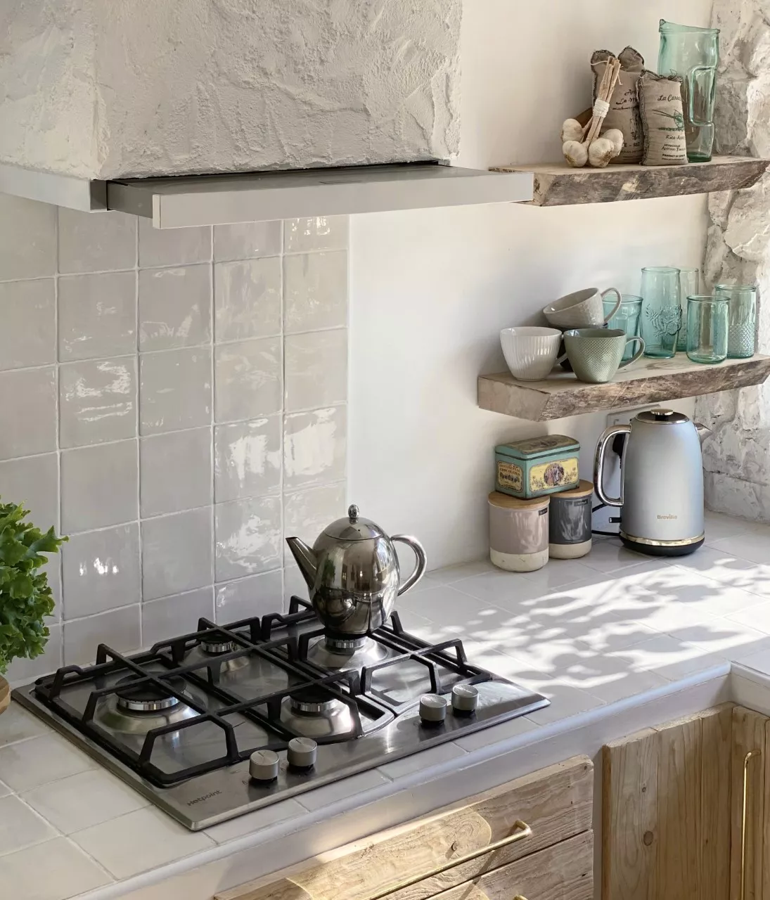 A tiled kitchen countertop with a gas stovetop and raw wood shelves.
