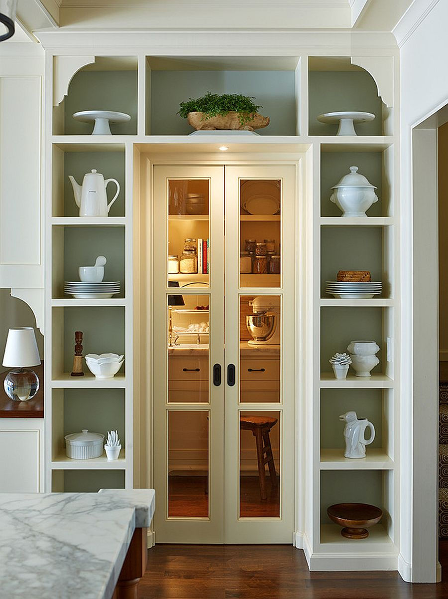 A built-in display shelving unit surround a door to a work area. There are a few display lights and the shelving frames the door.