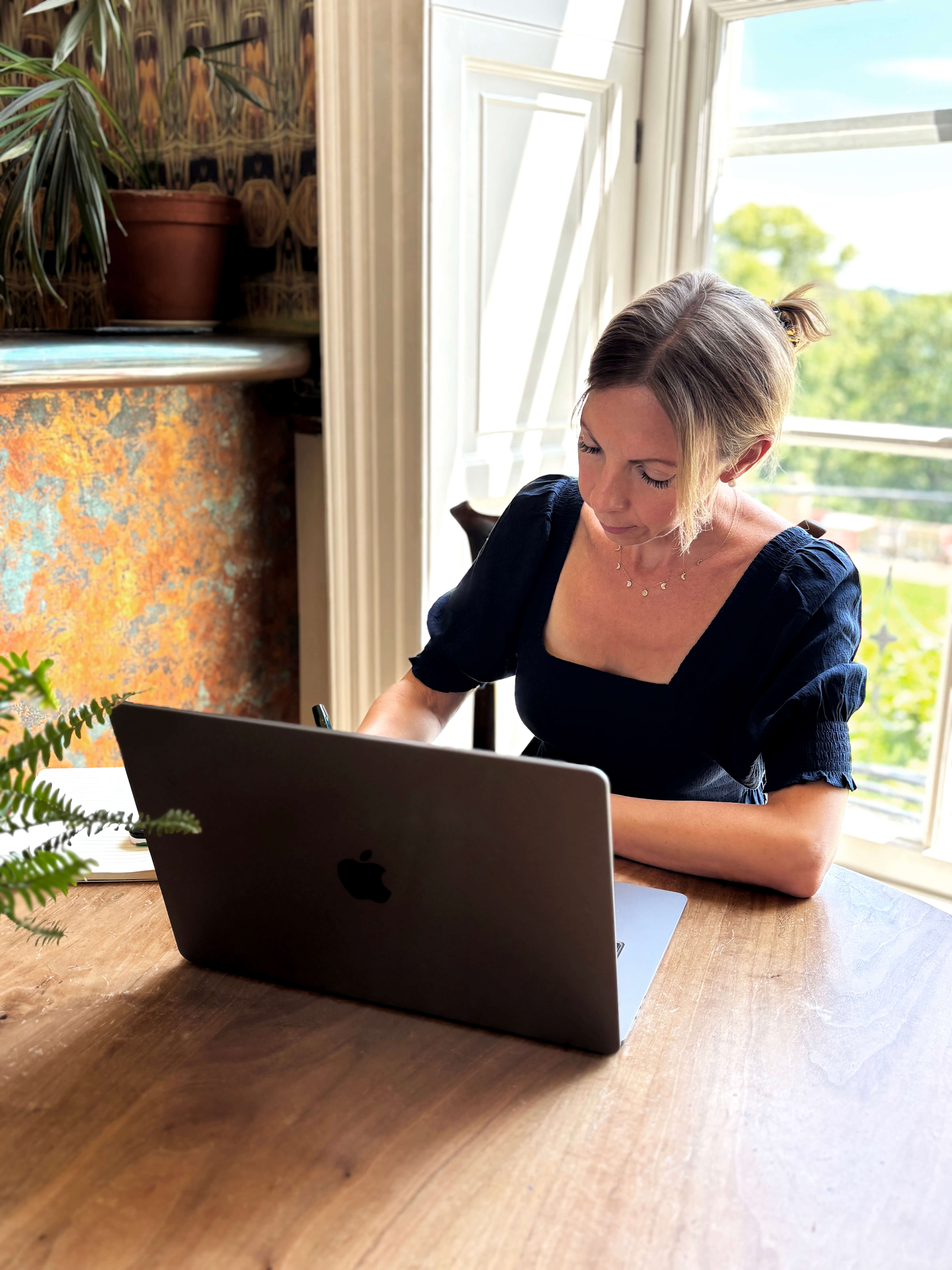 woman at a desk with laptop and blue dress 