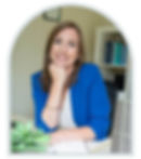 woman at white desk with blue blaizer and white top hand by chin book in background plant in forground