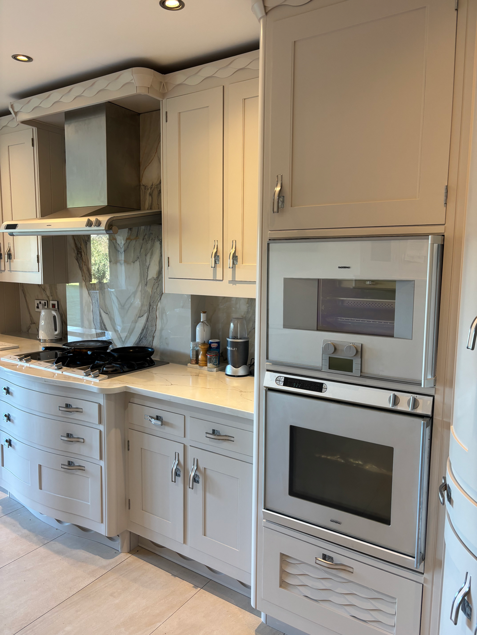 Transformed bespoke kitchen with hand-sprayed cabinetry in Farrow & Ball Stirrabout No.300, showcasing a brighter, modern aesthetic with soft neutral tones and preserved woodwork detail.