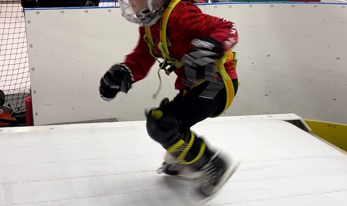 Young child in hockey gear skating on an indoor rink