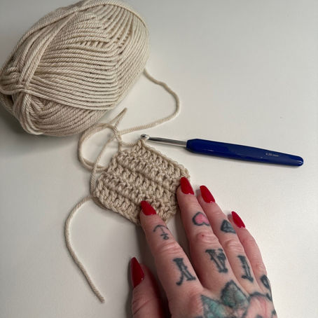 Crochet hook and yarn creating a fabric of double crochet stitches, demonstrating the double crochet technique step by step.