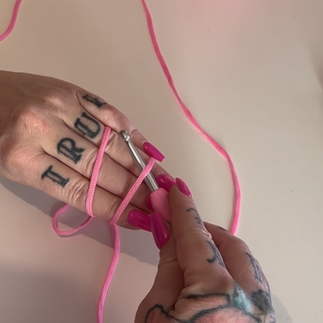 Crochet hook reaching under the front yarn strand across the palm.