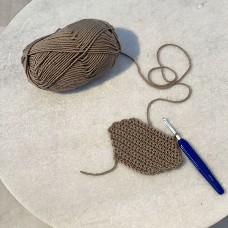 Crochet sample showing how increases and decreases shape a project, with yarn and hook included.