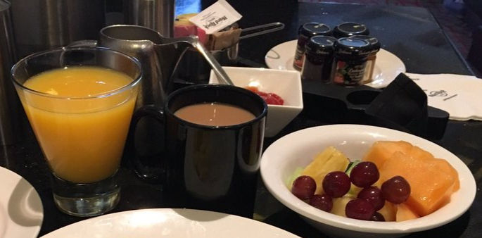 Vaso con jugo, taza de café y tazón de frutos