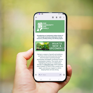 A hand holds a phone displaying an email newsletter from "One Community One Family." Green background with text about Southeastern Indiana services.