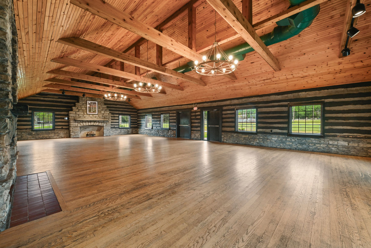 Event hall with windows and wooden beams across the ceiling.