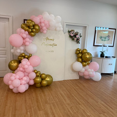 A pink, white, and gold balloon arch framing a custom "Athena's Confirmation" photo backdrop, styled for a 50-guest private celebration catered by Founding Farmers Co. Catering & Events in the DC metro area.