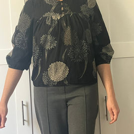Melissa wears the Beltane Top B, a yoked peasant blouse with three-quarter sleeves and frog closures at the center front.