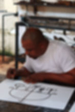 O artista em seu ateliê enquanto assina uma serigrafia que corresponde a uma das esculturas de ferro.