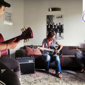 Mish giving a guitar lessons to adults at the studio. Mish helped both students buy their own guitars.