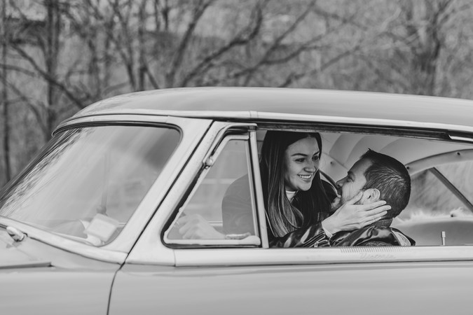 man and woman couple in an antique red car for valentines day pictures