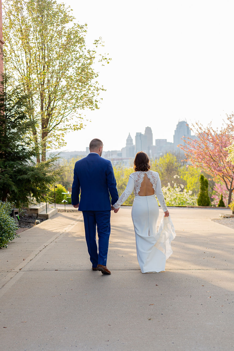 bride and groom walking away with Cincinnati skyline