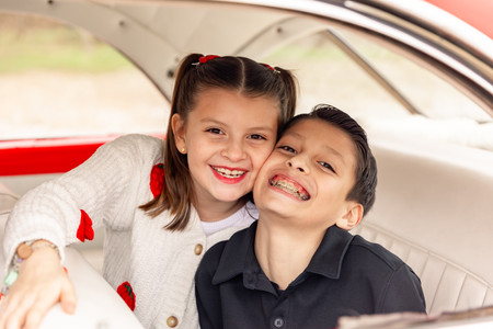 siblings sitting in an antique red car for valentines day pictures