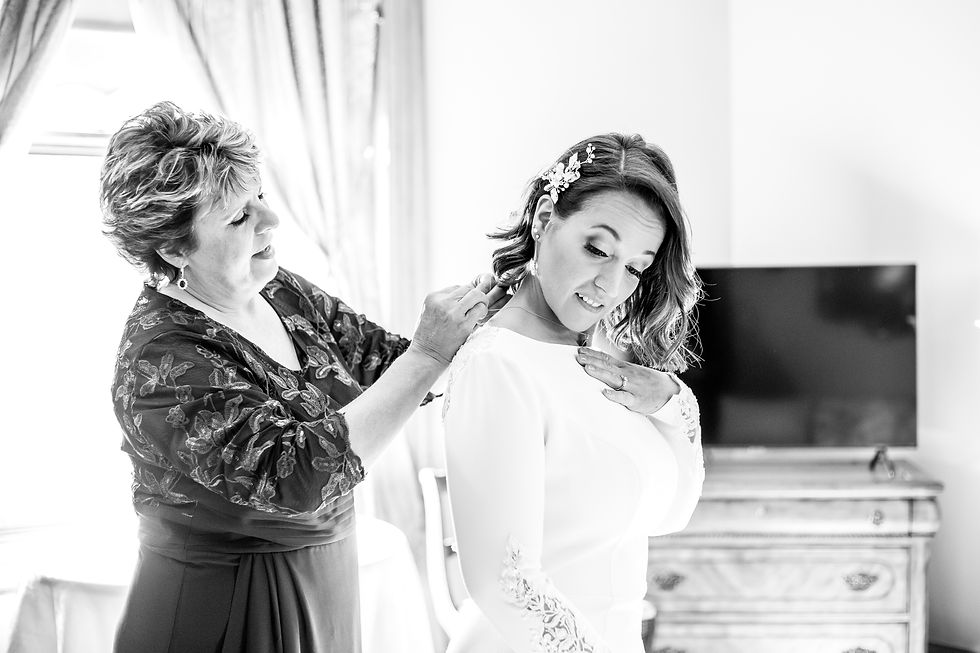 mother of the groom putting on bride's necklace