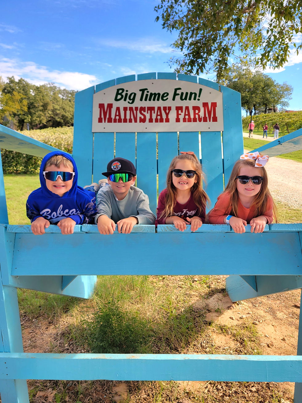 Four kids with sunglasses pose at a chair photo op at Mainstay Farm