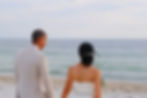 bride and groom walking along a shore