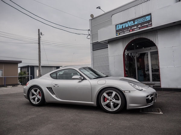 Drive. MOTOR SPORTの店頭に停車するシルバーのポルシェ・ケイマン