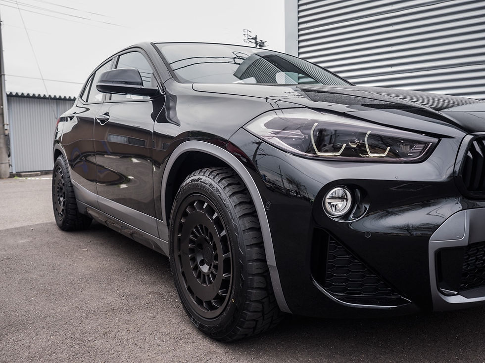 オフロードタイヤと黒のホイールを装着した黒いBMWのSUV