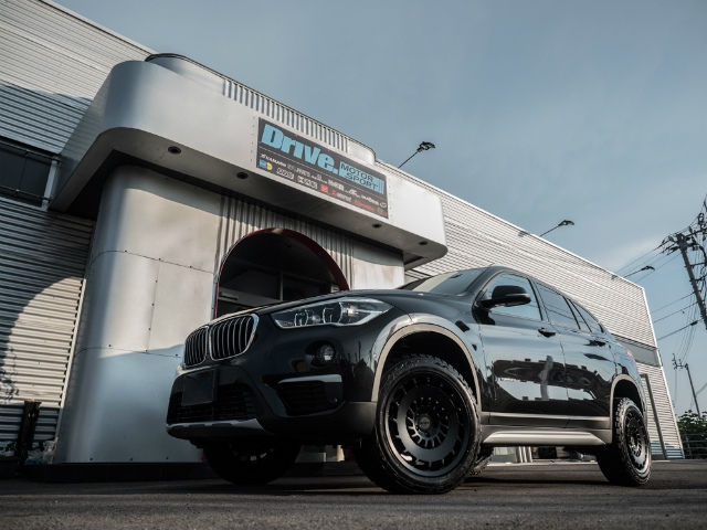 Drive. MOTOR SPORTの看板前に停まる黒のBMW SUV