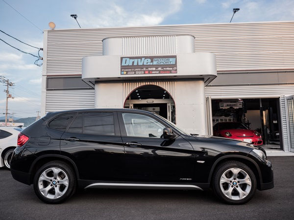 Drive. MOTOR SPORT店舗前に停車する黒のBMW X1