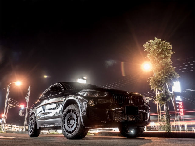 夜の街灯の下に駐車された、黒いオフロード仕様のBMW SUV
