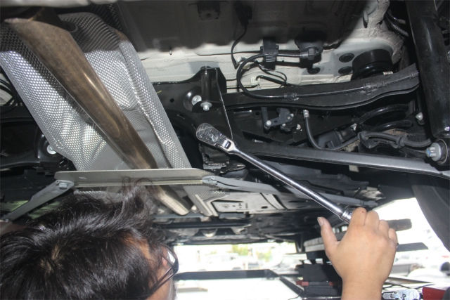 ラチェットレンチで車の足回りを整備するメカニックの手元