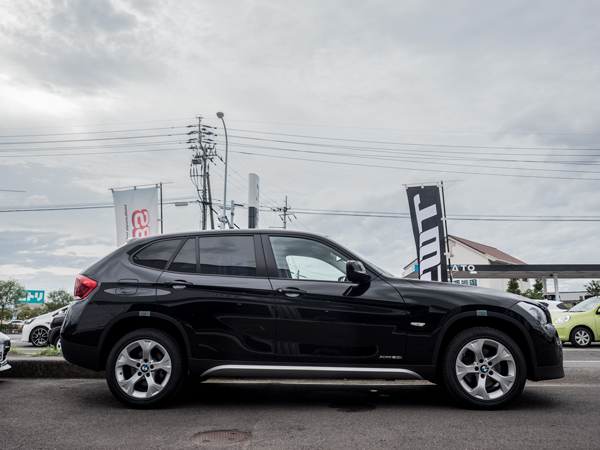 屋外の駐車場に停車している黒色のBMW X1の左側面